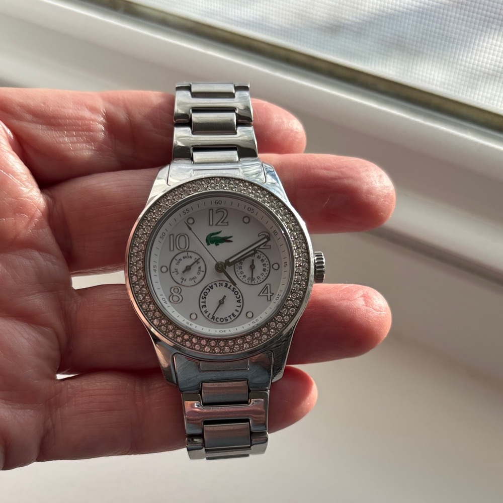 Lacoste stainless steel watch with pavé crystals surrounding watch face.